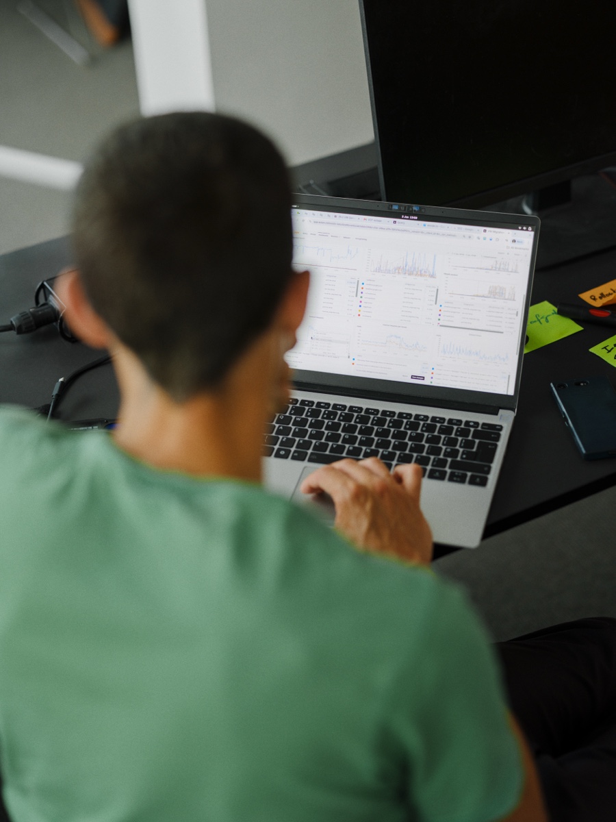 A teammate in a green shirt working at a laptop