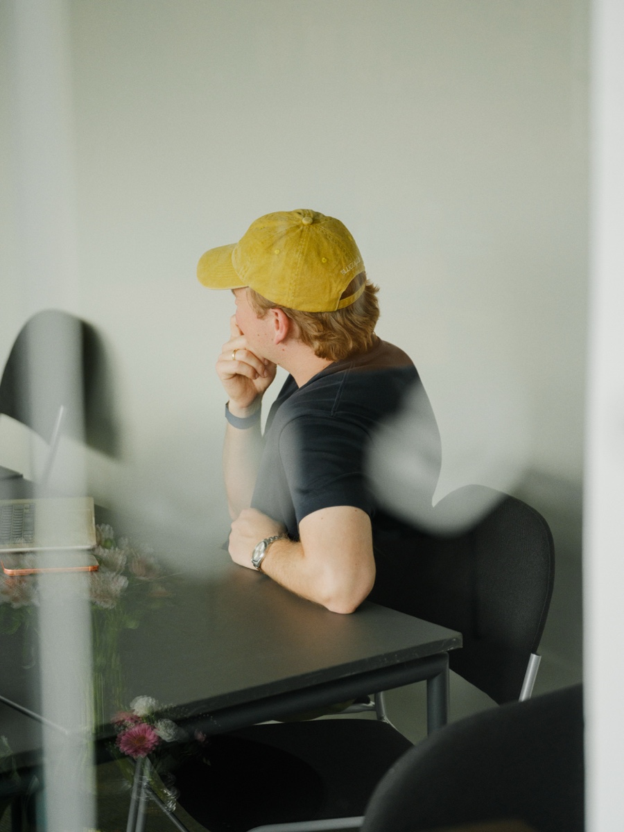 A teammate in a yellow beanie, lit by warm window light